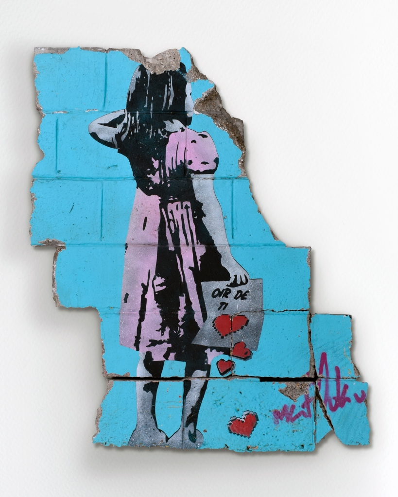 Street art depicting a nostalgic girl holding a letter that has dropped
love. This graffito was rescued from part of a former cinder block wall of
a destroyed shop.